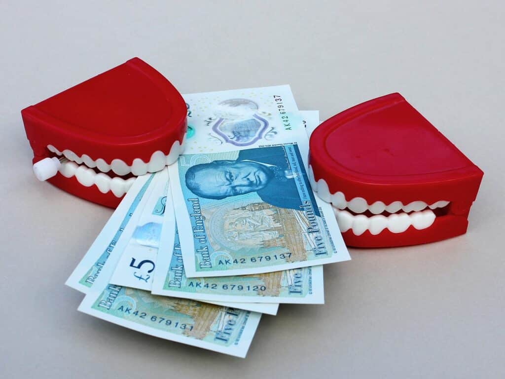 Dientes mordiendo fajo de dinero